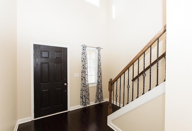 entryway with stairs, wood finished floors, baseboards, and a towering ceiling