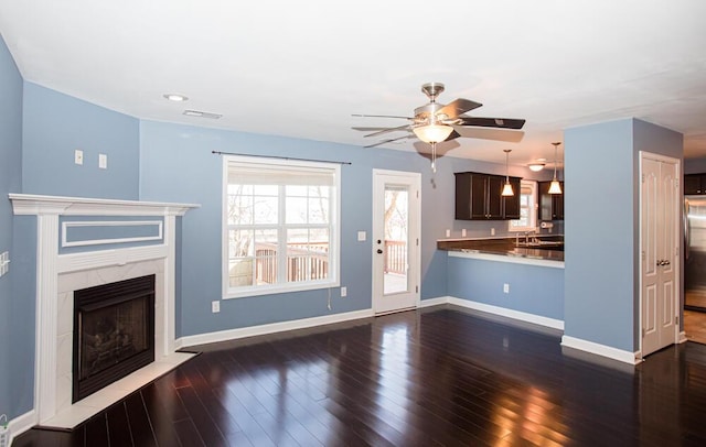 unfurnished living room featuring visible vents, dark wood-type flooring, a sink, a high end fireplace, and baseboards