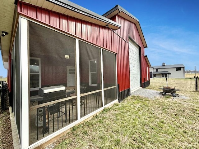 view of side of property featuring fence, board and batten siding, a sunroom, and a lawn