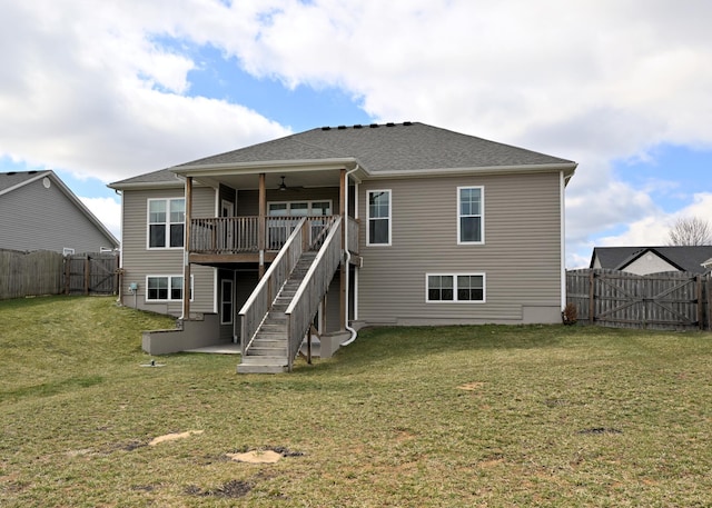 rear view of house featuring stairway, a lawn, a ceiling fan, and a gate