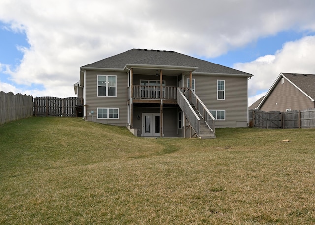 rear view of house with stairway, a yard, and a fenced backyard