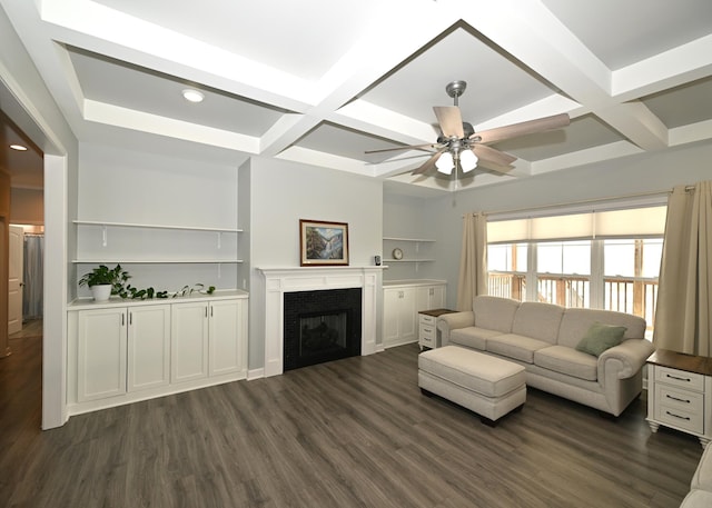 living area with beam ceiling, coffered ceiling, a fireplace, ceiling fan, and dark wood-style flooring