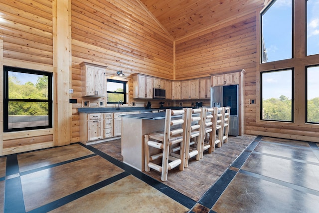 kitchen with dark countertops, a kitchen island, a kitchen bar, stainless steel appliances, and a sink