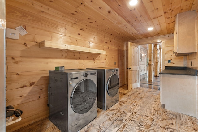 laundry area featuring wooden walls, washer and dryer, wooden ceiling, light wood-style floors, and cabinet space