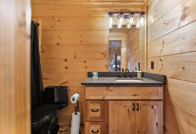 bathroom with vanity, wooden walls, and toilet