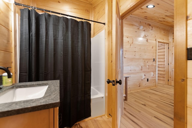 bathroom featuring shower / bath combo, wood finished floors, recessed lighting, wooden walls, and vanity