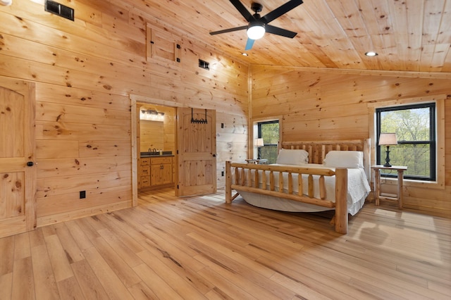 bedroom with lofted ceiling, light wood-style floors, and wood walls