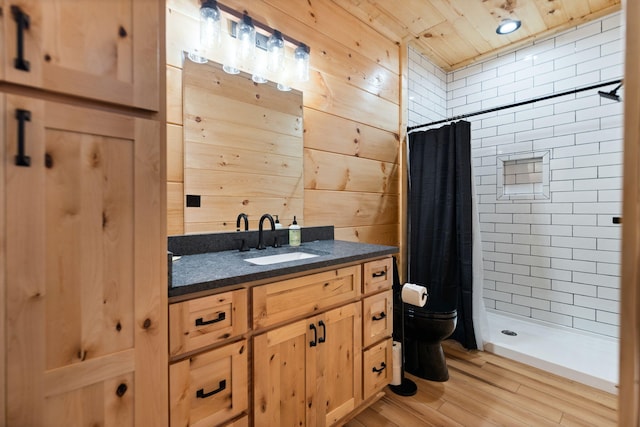 full bath featuring toilet, wood finished floors, wooden walls, a shower stall, and vanity