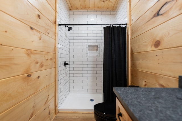 full bath with wooden walls, a stall shower, toilet, and vanity