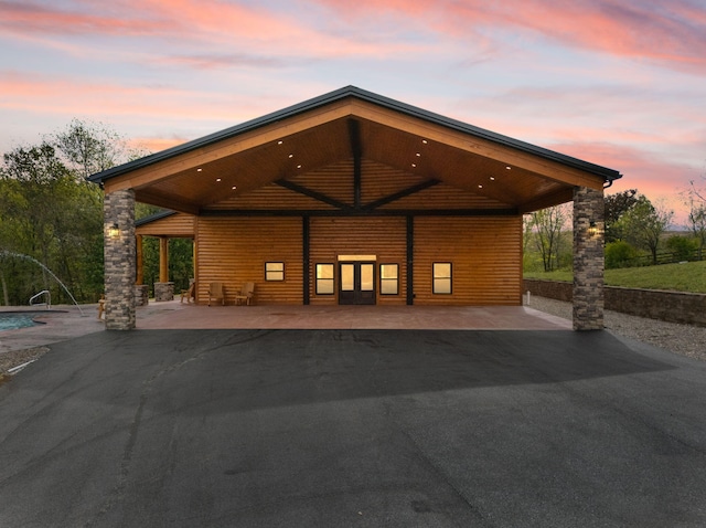 back of property at dusk with aphalt driveway and faux log siding