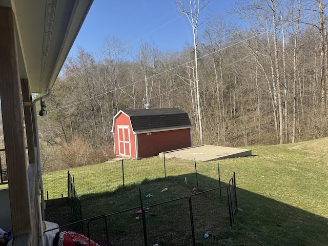 view of yard with a detached garage, a storage shed, an outdoor structure, and fence