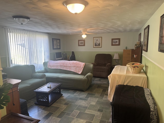 living area featuring ceiling fan and wainscoting