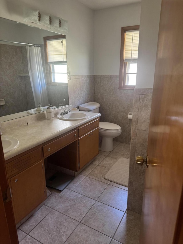 bathroom featuring tile patterned flooring, toilet, plenty of natural light, and a sink