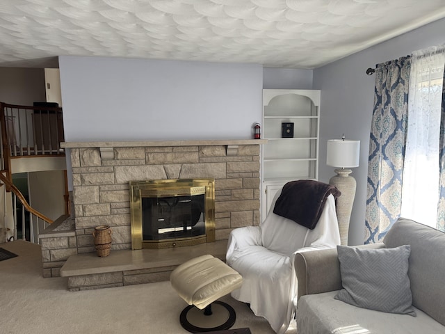 carpeted living area featuring a stone fireplace and stairs