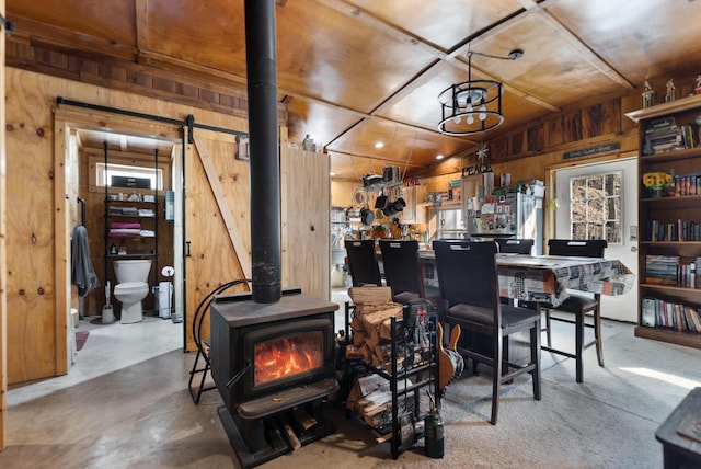 3860 Newfound Rd, Oneida, KY 40972 - living room featuring wood walls, a wood stove, a barn door, and concrete floors