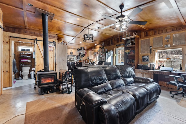 3860 Newfound Rd, Oneida, KY 40972 - living room with wood walls, a wood stove, ceiling fan, and concrete floors