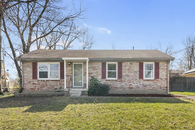 ranch-style house featuring a front yard, fence, brick siding, and roof with shingles