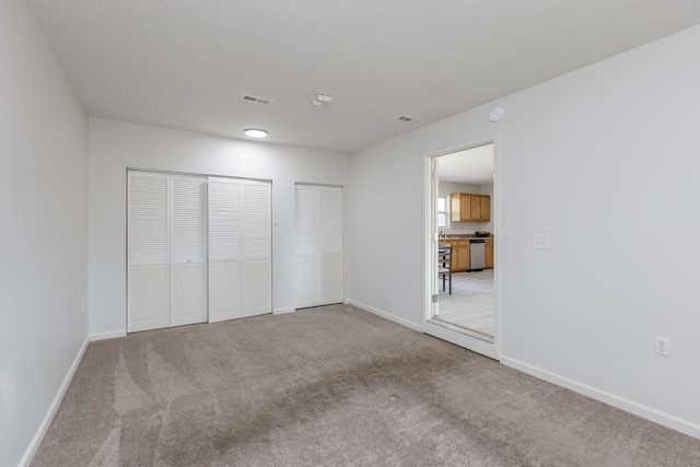 unfurnished bedroom featuring visible vents, a textured ceiling, baseboards, and carpet floors