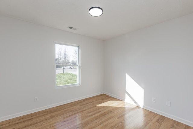 unfurnished room featuring light wood finished floors, visible vents, and baseboards