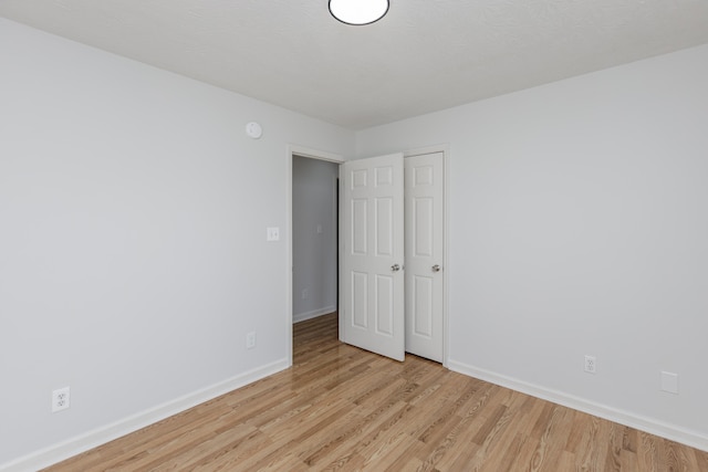 spare room featuring baseboards and light wood finished floors