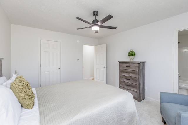 bedroom featuring light carpet, baseboards, ensuite bathroom, and ceiling fan