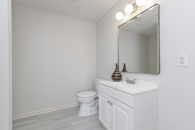 half bathroom featuring baseboards, toilet, and vanity