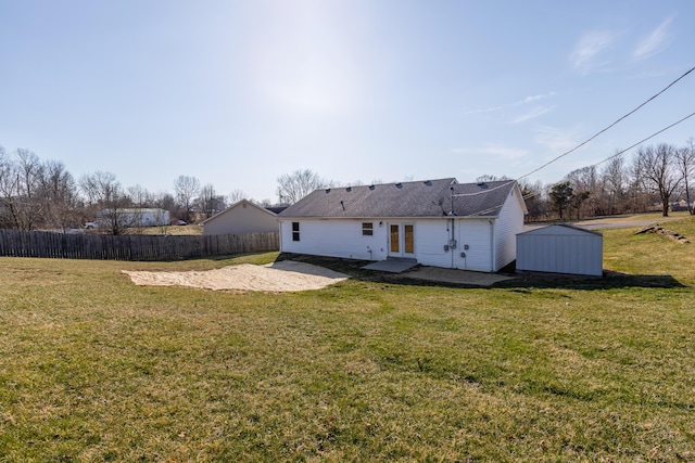 rear view of property with a lawn, a patio, fence, french doors, and an outdoor structure