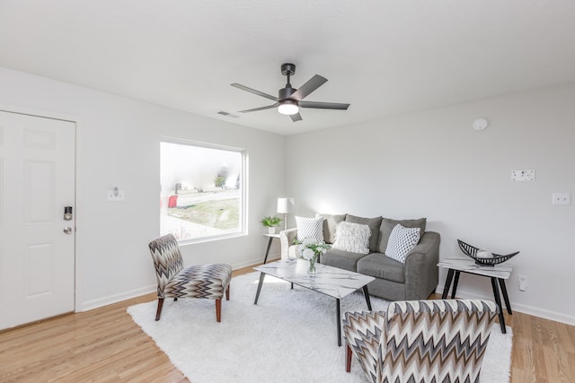 living room with visible vents, baseboards, light wood-style floors, and a ceiling fan