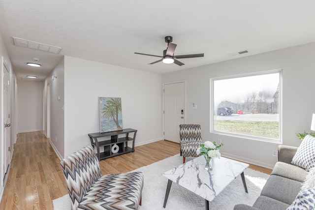 living area with baseboards, visible vents, and light wood-type flooring