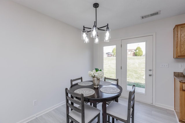 dining area featuring visible vents, baseboards, an inviting chandelier, and light wood finished floors