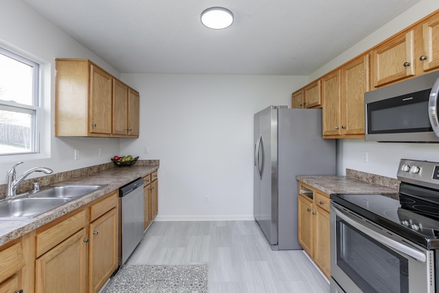 kitchen featuring a sink, light floors, baseboards, and stainless steel appliances