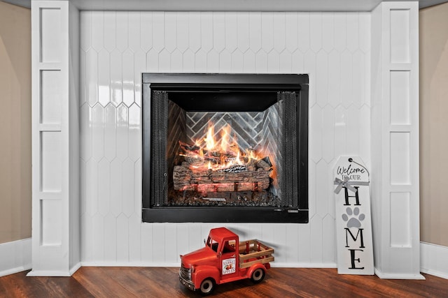 room details featuring baseboards, a lit fireplace, and wood finished floors