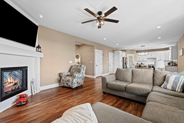 living room with a ceiling fan, a glass covered fireplace, wood finished floors, recessed lighting, and baseboards