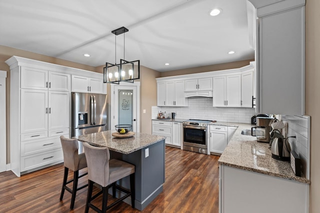 kitchen featuring dark wood finished floors, custom range hood, light stone counters, and appliances with stainless steel finishes