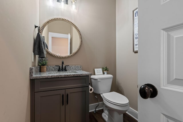 half bathroom with toilet, vanity, and baseboards