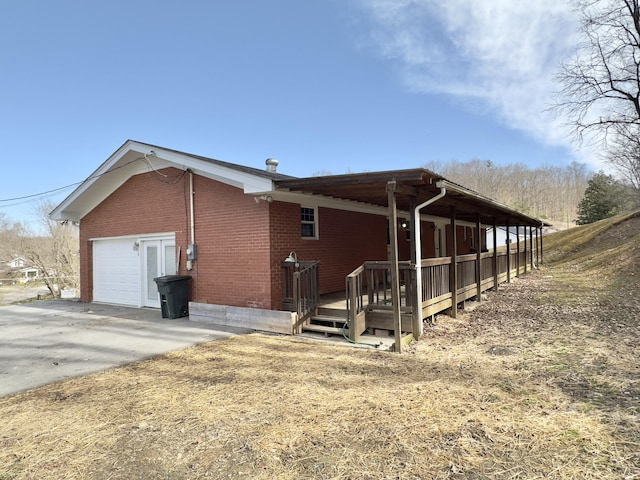 view of side of property with a garage, brick siding, and driveway