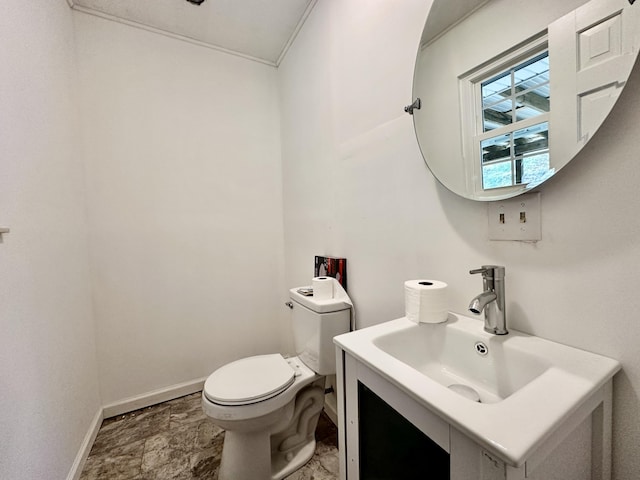 bathroom with toilet, vanity, and baseboards