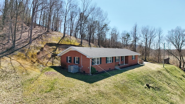 view of side of property with crawl space, brick siding, central AC unit, and a lawn