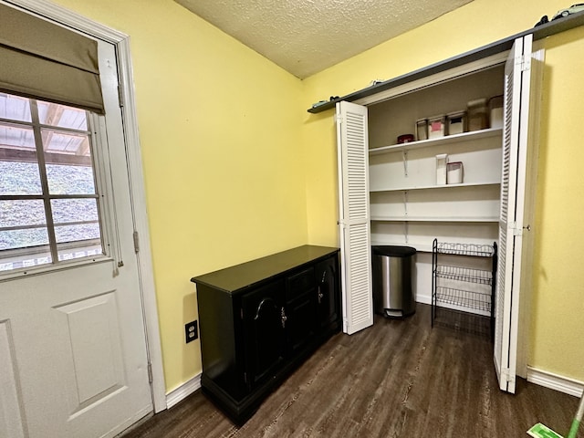 interior space featuring a textured ceiling, baseboards, and wood finished floors