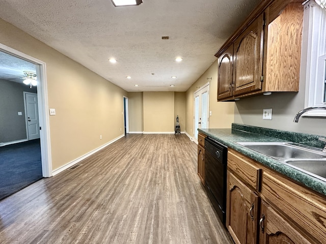 kitchen featuring a sink, baseboards, black dishwasher, and dark countertops