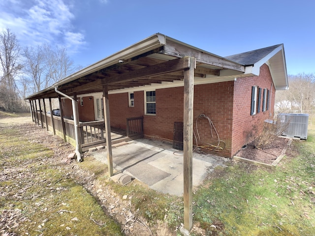 back of property featuring a carport, central air condition unit, and brick siding