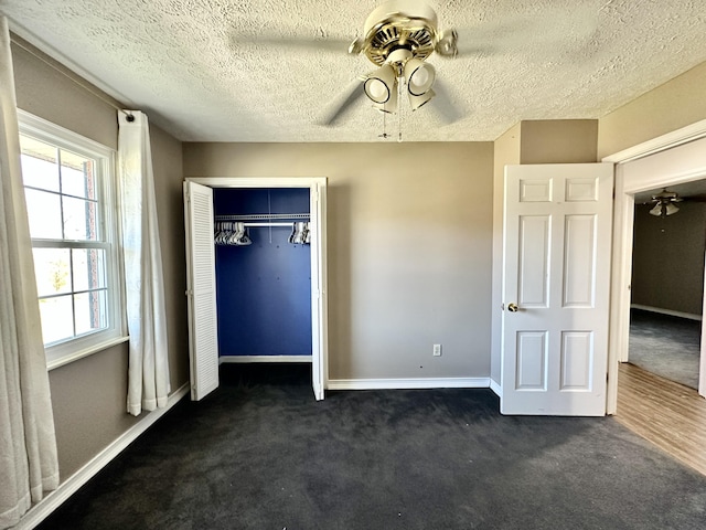 unfurnished bedroom with dark colored carpet, a closet, baseboards, and ceiling fan