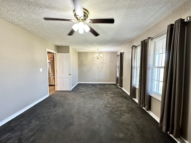 empty room with ceiling fan with notable chandelier, baseboards, dark colored carpet, and a textured ceiling