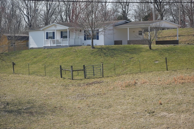 view of front of house with a porch, fence, a front yard, and a carport