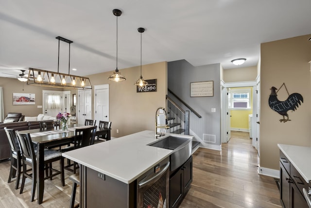 kitchen featuring wood finished floors, visible vents, a sink, light countertops, and open floor plan