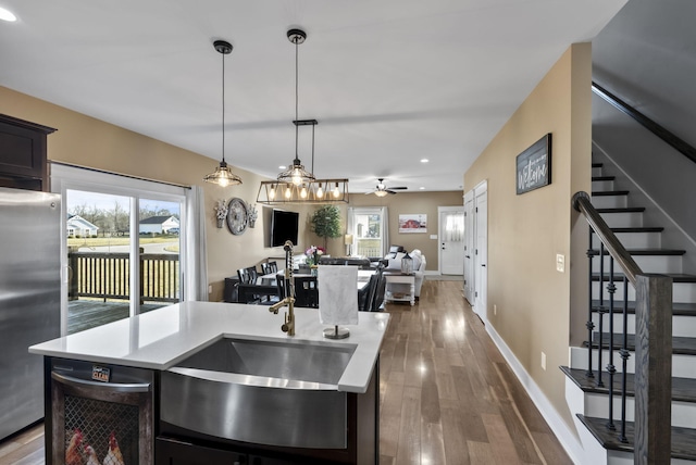 kitchen featuring a sink, wood finished floors, open floor plan, freestanding refrigerator, and light countertops