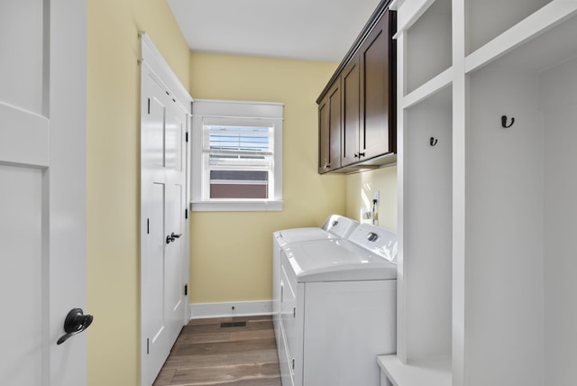 laundry area featuring washer and dryer, baseboards, cabinet space, and wood finished floors