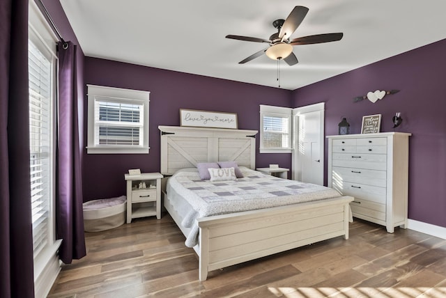 bedroom with a ceiling fan, wood finished floors, and baseboards