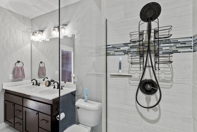 bathroom with double vanity, tiled shower, toilet, and a sink