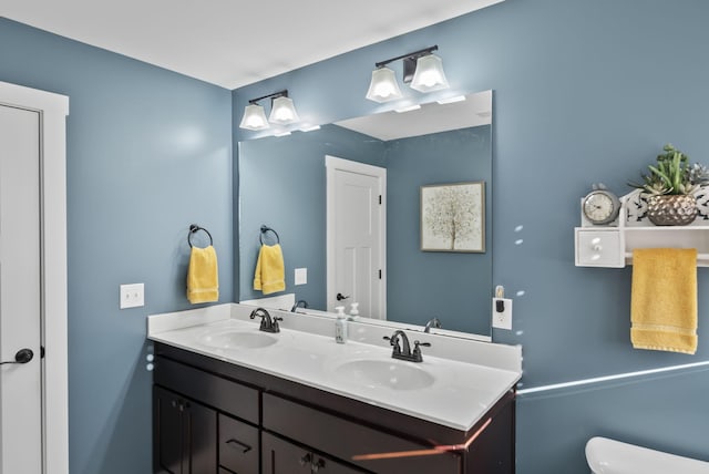 bathroom with double vanity, toilet, and a sink